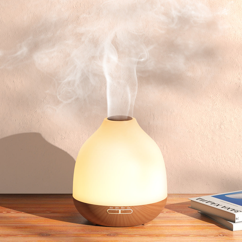 Ultrasonic aroma diffuser emitting steam with wood grain base on wooden table against a neutral background